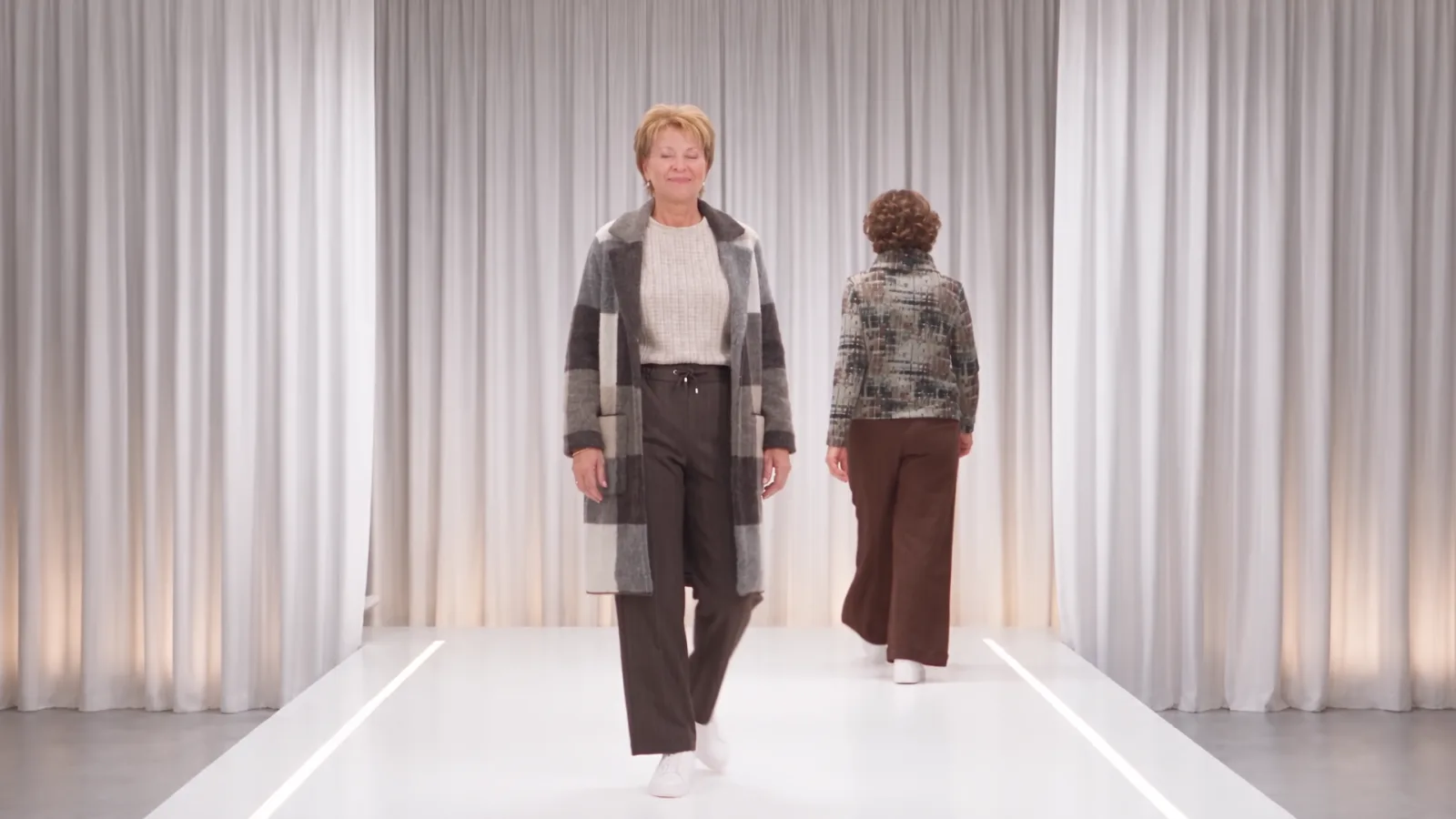 Deux mannequins IA sur le podium virtuel - lumière et décor constants